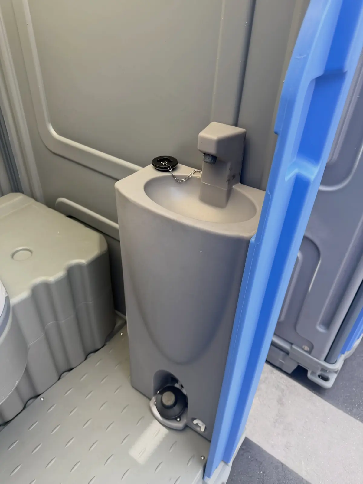 Foot-pump sink with soap and paper towels inside a deluxe portable toilet
