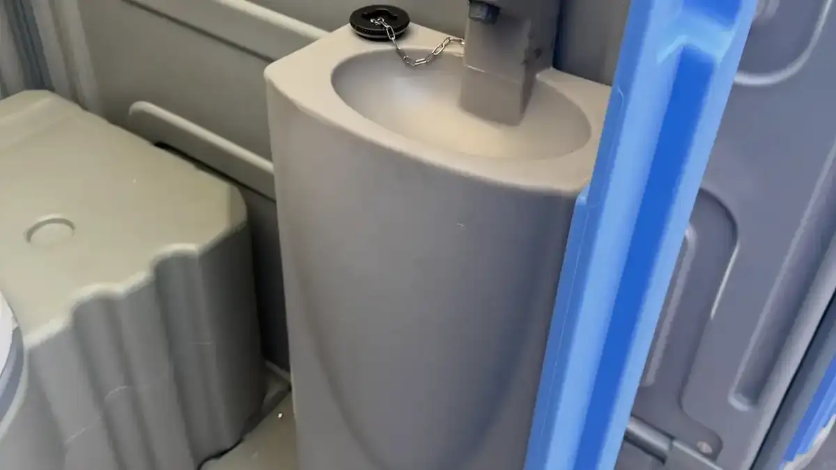 Inside a deluxe portable toilet with a foot-pump sink, soap and towels