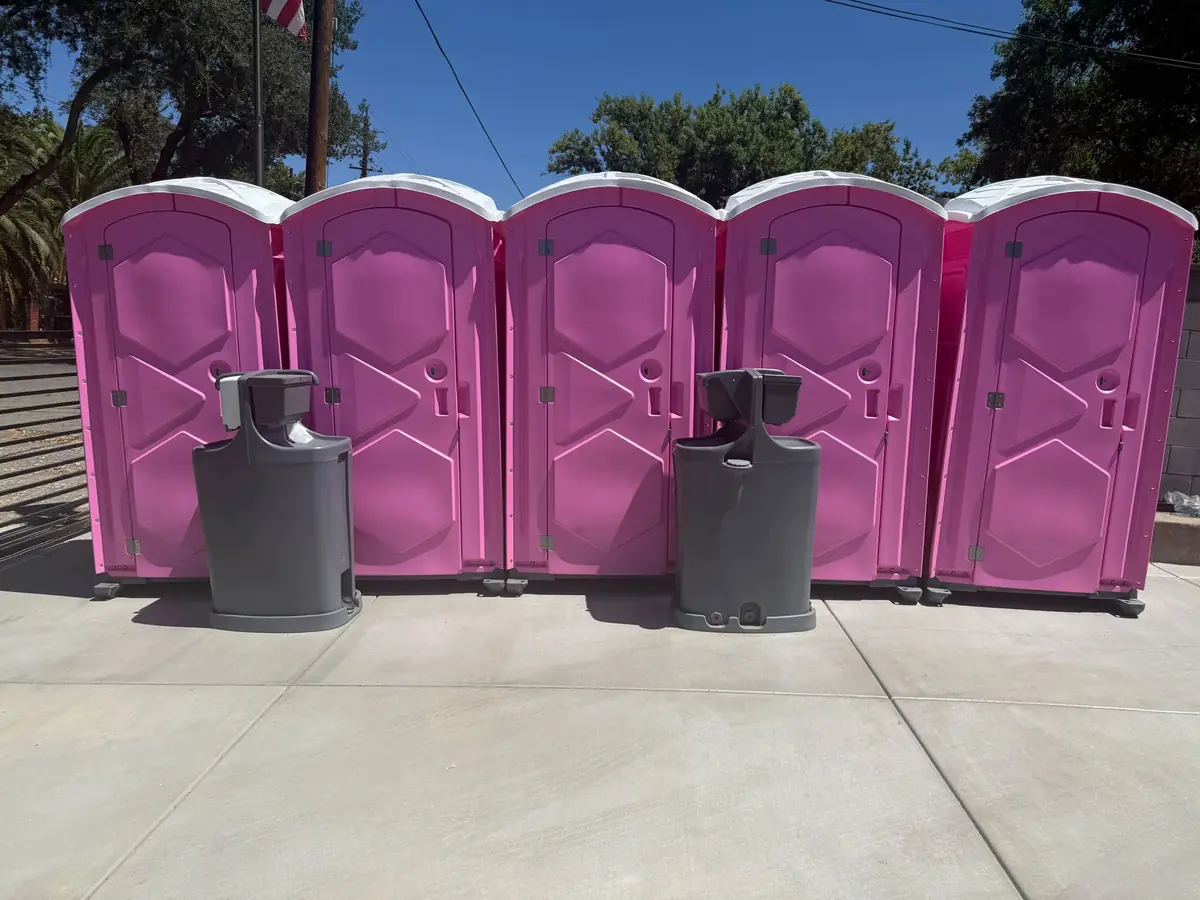 Row of portable toilets with two hand-wash stations set up on a paved lot