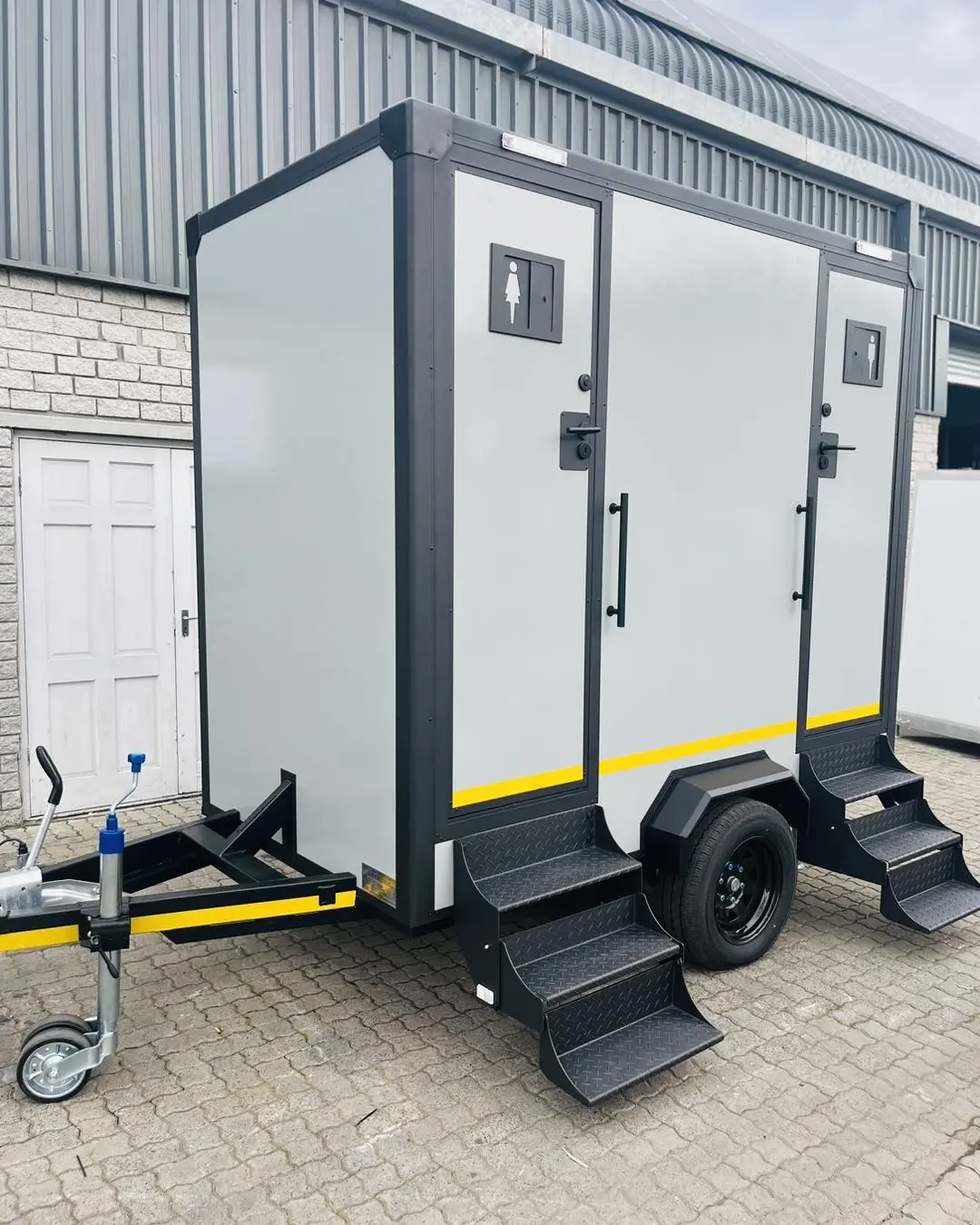 Restroom trailer with steps and handrails leading to the stall doors