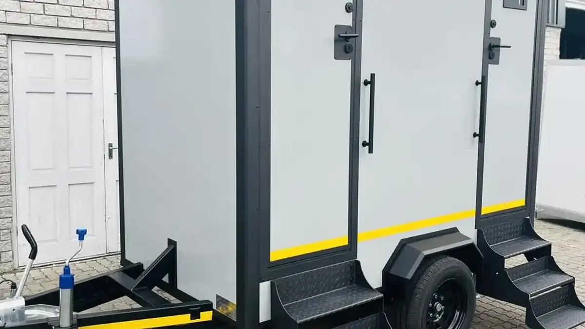 Restroom trailer with metal steps and a railing leading to the doors
