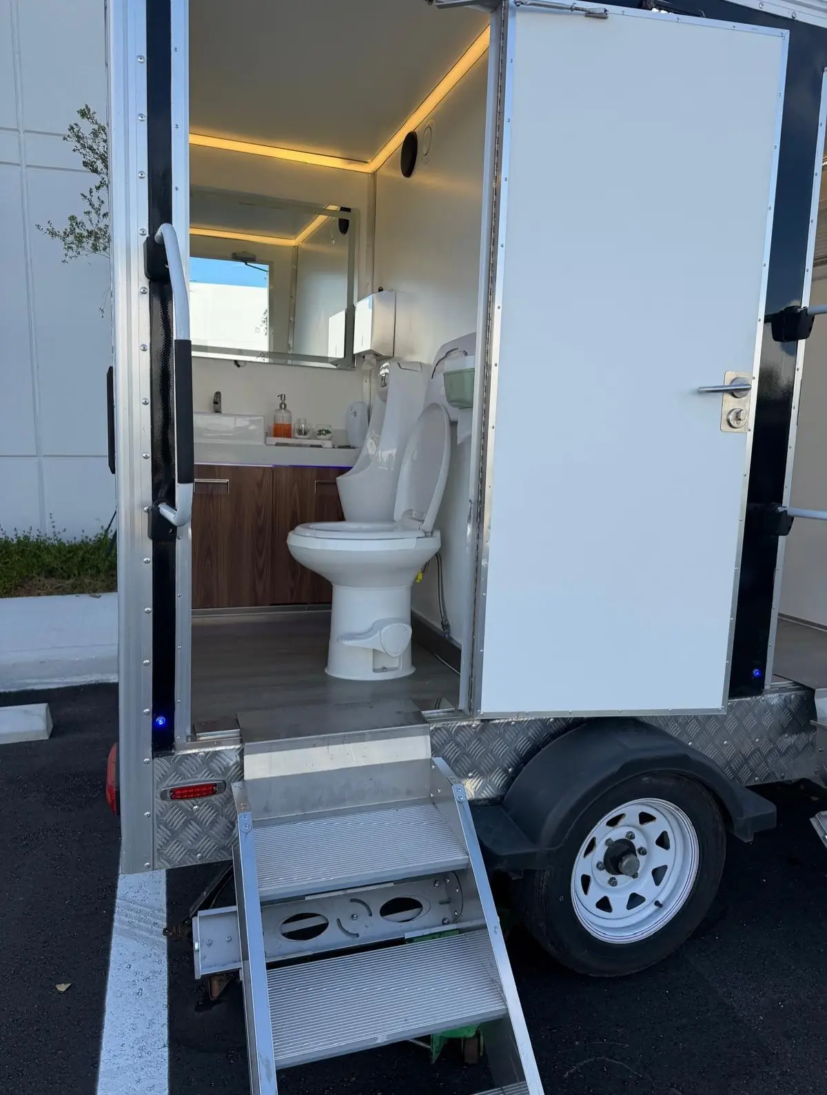 Restroom trailer interior with a vanity sink, mirror and soft lighting
