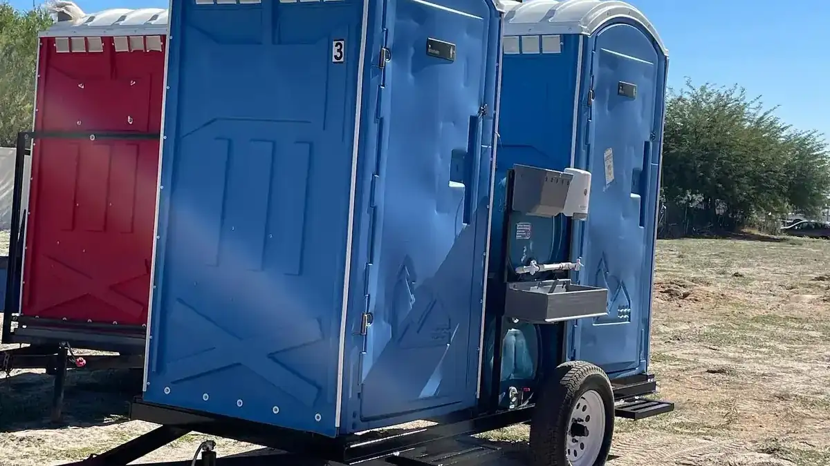 Towable portable toilet trailer parked at a construction site