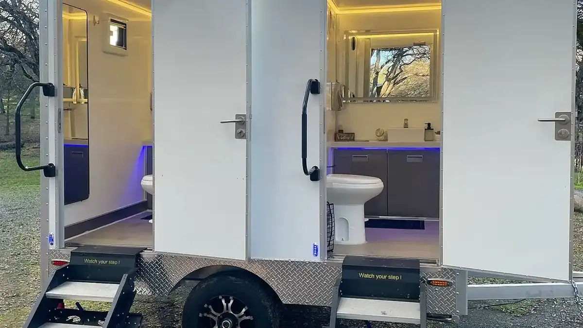 Two-stall restroom trailer with lights on at dusk